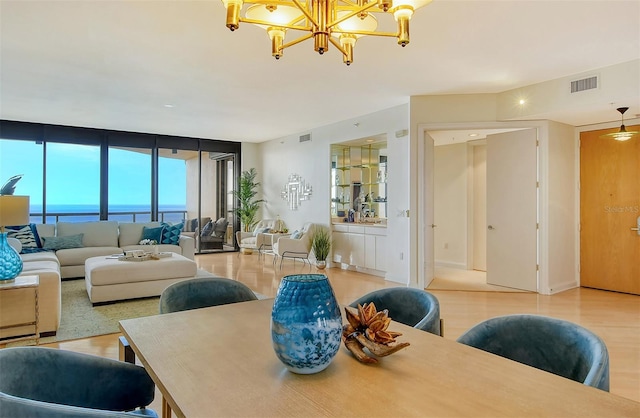 dining area featuring an inviting chandelier, expansive windows, a water view, and wood-type flooring