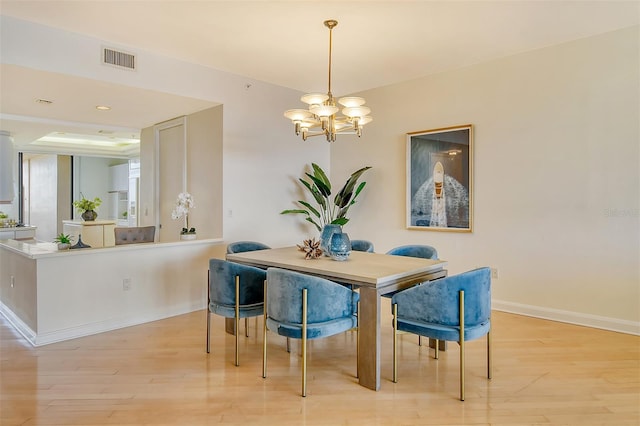 dining area with light wood-type flooring and an inviting chandelier