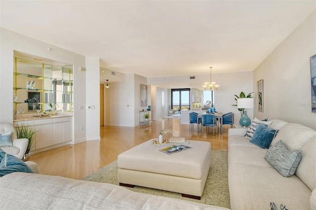 living room with light hardwood / wood-style floors and an inviting chandelier