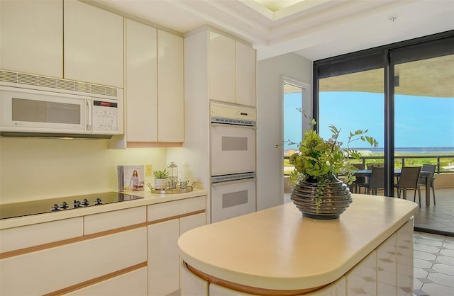415 L Ambiance Dr Unit C703, Longboat Key, FL 34228 - kitchen featuring white appliances, light countertops, a center island, and light tile patterned flooring