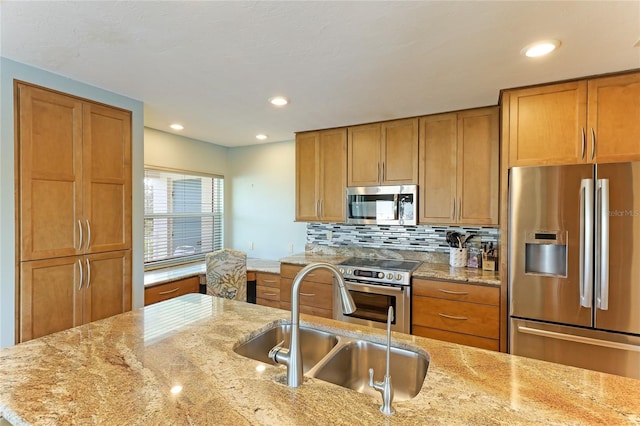 kitchen featuring light stone counters, sink, decorative backsplash, and appliances with stainless steel finishes