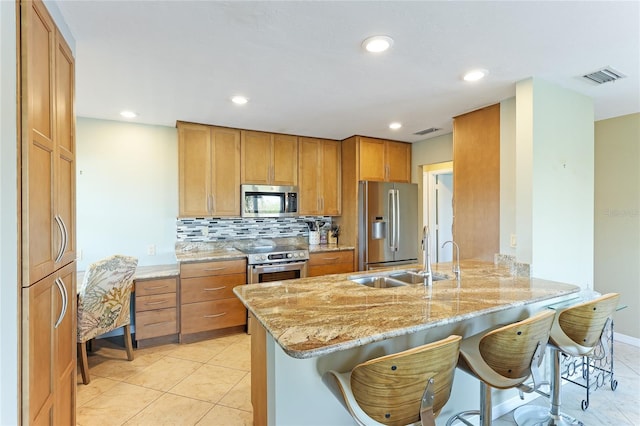 kitchen featuring tasteful backsplash, stainless steel appliances, a kitchen bar, light stone countertops, and kitchen peninsula