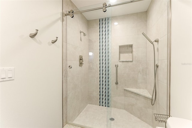 bathroom featuring a shower with door and toilet