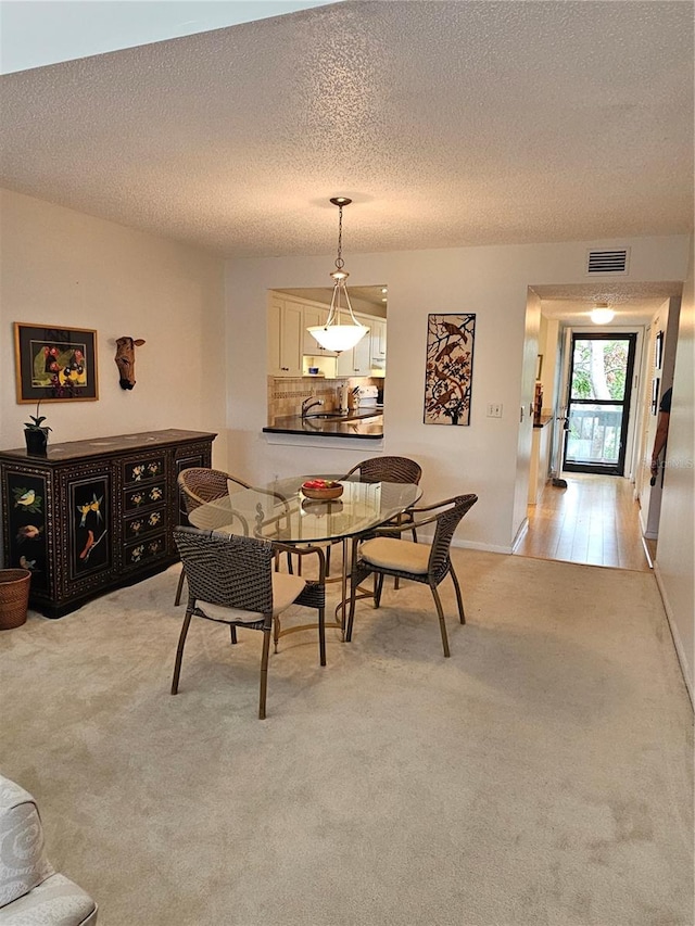 dining space with a textured ceiling and light hardwood / wood-style flooring