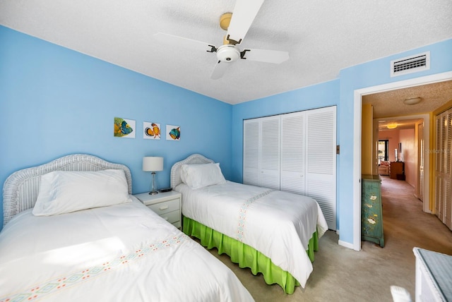 bedroom with ceiling fan, light colored carpet, a textured ceiling, and a closet