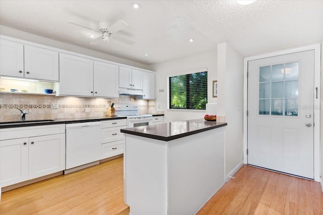 1519 Pelican Point Dr Unit 292, Sarasota, FL 34231 - kitchen with white appliances, under cabinet range hood, dark countertops, light wood-type flooring, and a textured ceiling