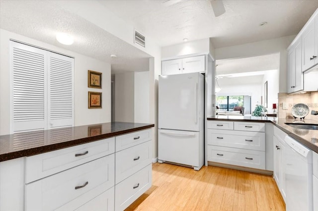1519 Pelican Point Dr Unit 292, Sarasota, FL 34231 - kitchen with white appliances, dark countertops, white cabinets, and light wood-style flooring