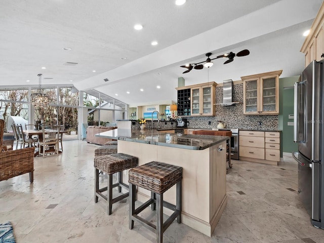 kitchen featuring wall chimney exhaust hood, stainless steel appliances, a wall of windows, kitchen peninsula, and a kitchen bar