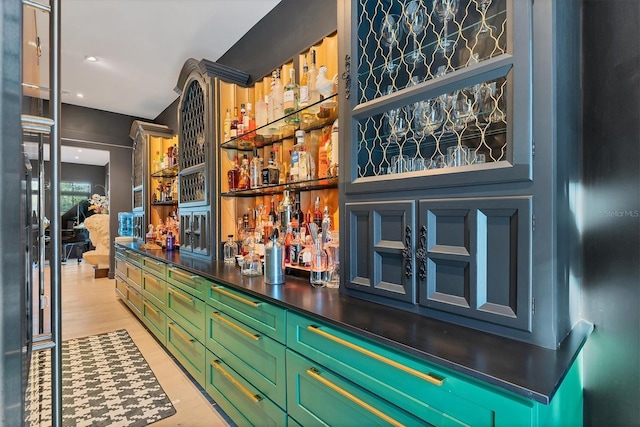 bar with green cabinetry and light wood-type flooring