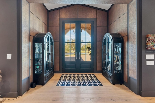 entrance foyer featuring french doors, vaulted ceiling, and light hardwood / wood-style flooring