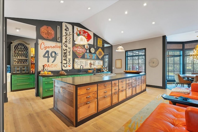 bar featuring sink, green cabinets, vaulted ceiling, and light wood-type flooring