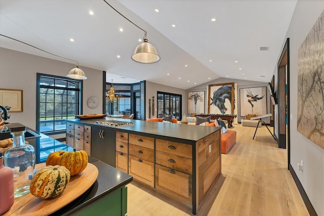 kitchen with lofted ceiling, hanging light fixtures, a kitchen island, and light wood-type flooring