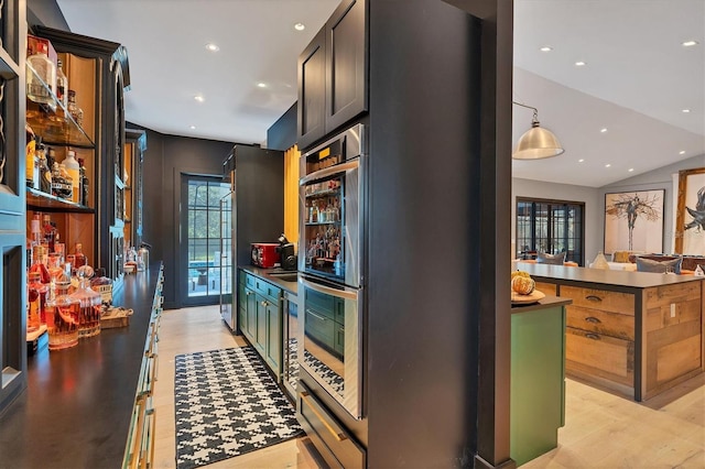 kitchen with hanging light fixtures, lofted ceiling, stainless steel double oven, and light wood-type flooring