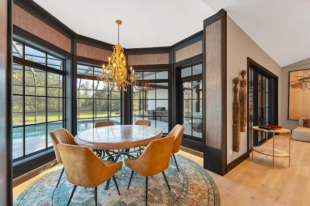 dining space with vaulted ceiling, a chandelier, and light hardwood / wood-style flooring