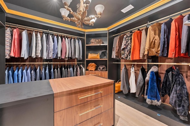 walk in closet with light wood-type flooring and a chandelier