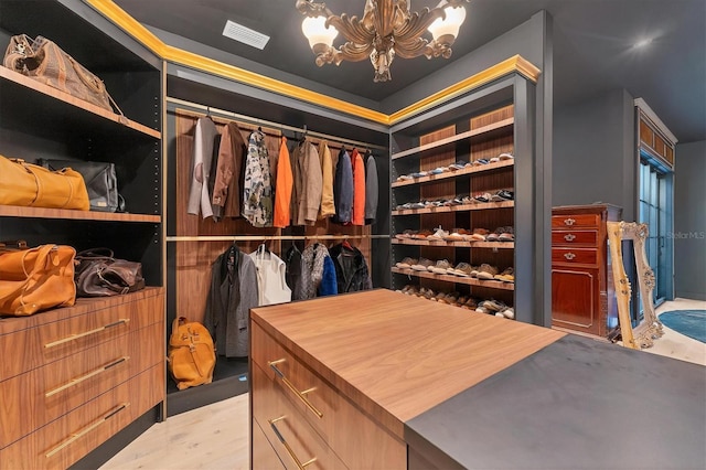 spacious closet with an inviting chandelier and light hardwood / wood-style floors