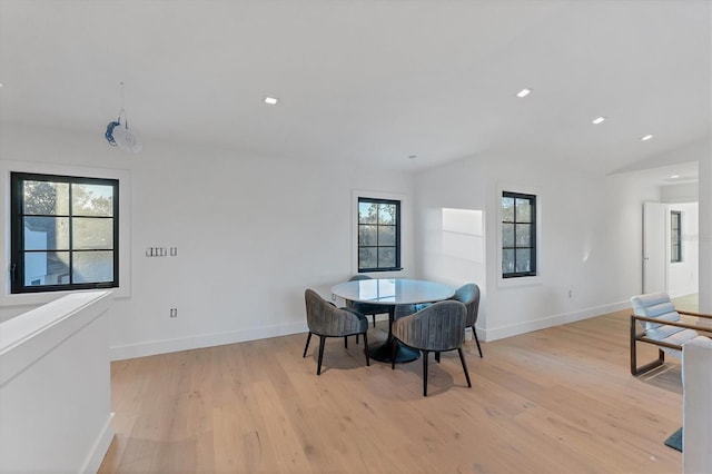 dining room with vaulted ceiling and light hardwood / wood-style floors