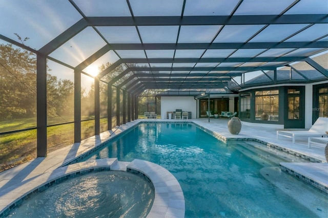 view of pool with an in ground hot tub, glass enclosure, and a patio area