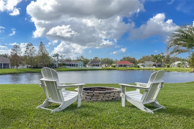 view of dock with a yard, a water view, a residential view, and an outdoor fire pit