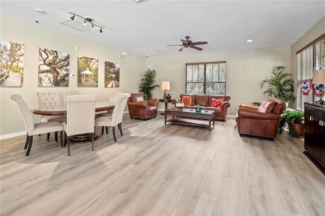 dining room featuring baseboards, light wood-style flooring, a textured ceiling, and ceiling fan