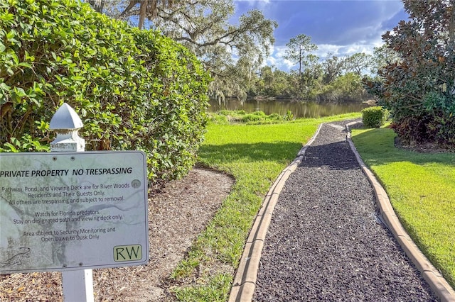 view of home's community with a water view and a lawn