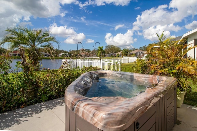 view of pool featuring a water view, a hot tub, and fence