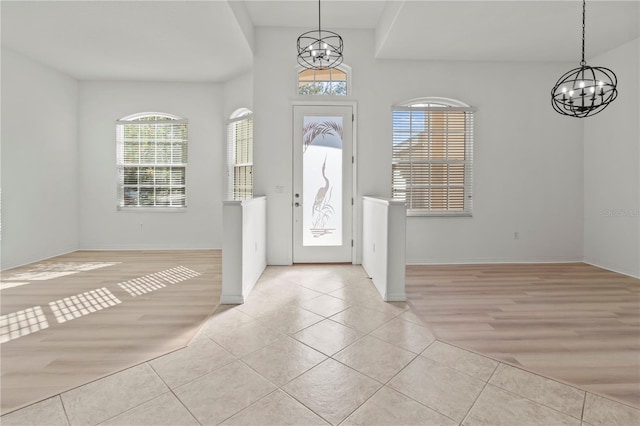 entrance foyer with light tile patterned floors, baseboards, and a chandelier