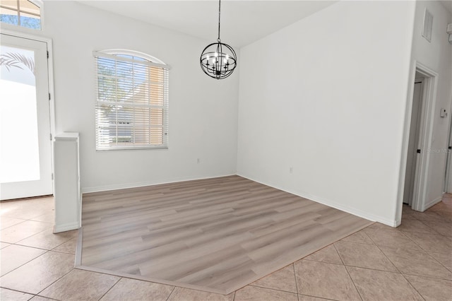 unfurnished dining area with light tile patterned floors, baseboards, and an inviting chandelier