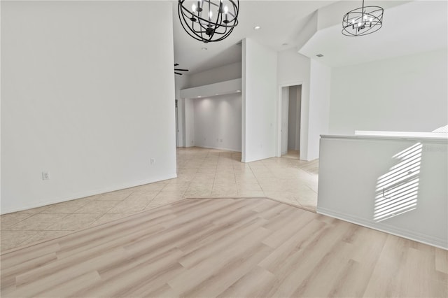 unfurnished room with baseboards, a notable chandelier, and wood finished floors