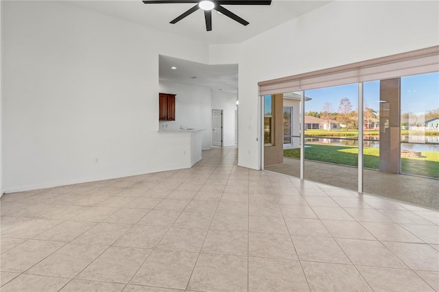 spare room featuring light tile patterned floors, a ceiling fan, baseboards, and a water view