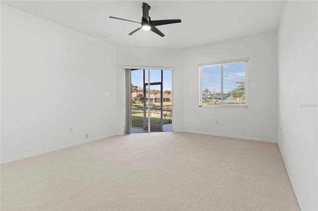 spare room featuring a ceiling fan, baseboards, and light carpet