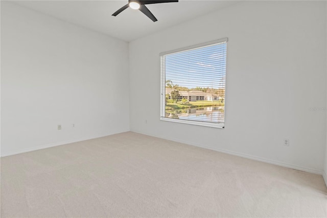 spare room featuring baseboards, light carpet, and ceiling fan