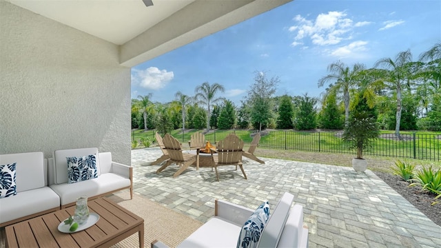 view of patio featuring ceiling fan and an outdoor living space with a fire pit