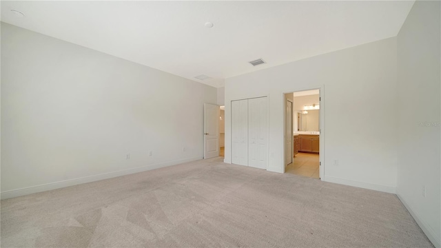 unfurnished bedroom with connected bathroom and light colored carpet