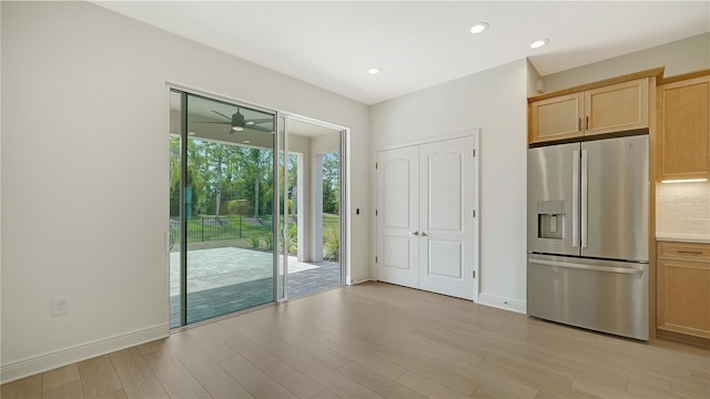 kitchen with stainless steel fridge with ice dispenser, light wood-type flooring, light brown cabinets, and backsplash