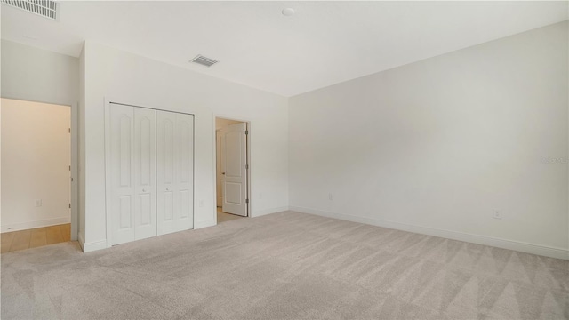 unfurnished bedroom with light carpet and a closet