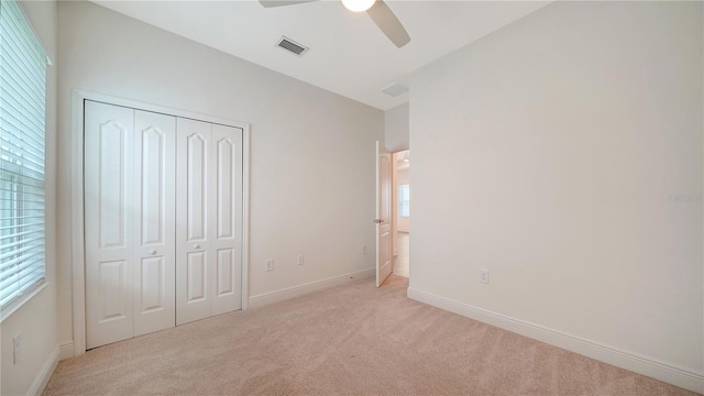 unfurnished bedroom with a closet, ceiling fan, and light colored carpet