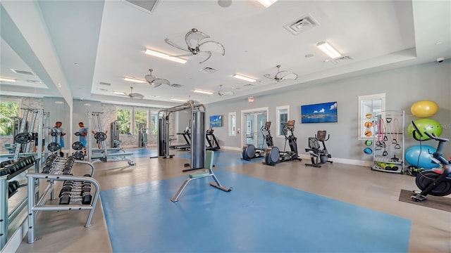 exercise room with a raised ceiling and ceiling fan