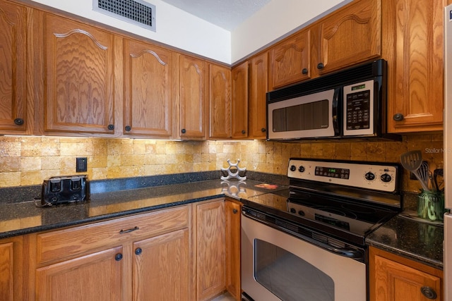 kitchen with backsplash, stainless steel appliances, and dark stone counters