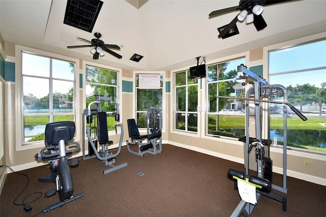 gym featuring ceiling fan, a water view, and dark carpet