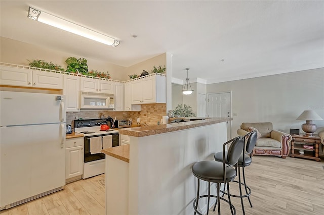 kitchen featuring white appliances, light hardwood / wood-style flooring, a breakfast bar, tasteful backsplash, and decorative light fixtures