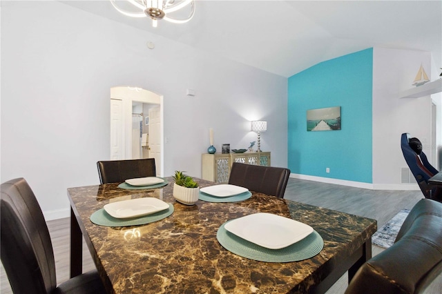 dining area with a notable chandelier, lofted ceiling, and hardwood / wood-style flooring