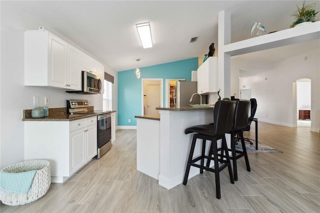 kitchen with white cabinets, decorative light fixtures, lofted ceiling, and stainless steel appliances