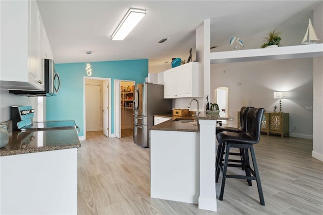 kitchen with white cabinetry, stainless steel appliances, hanging light fixtures, kitchen peninsula, and lofted ceiling