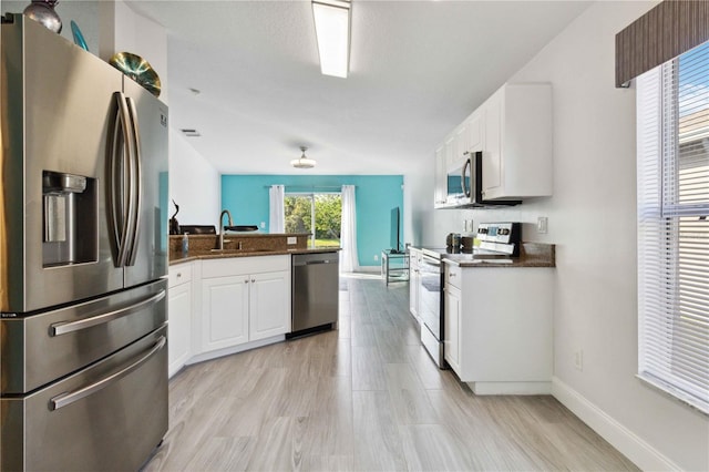 kitchen featuring white cabinetry, sink, light hardwood / wood-style flooring, and appliances with stainless steel finishes