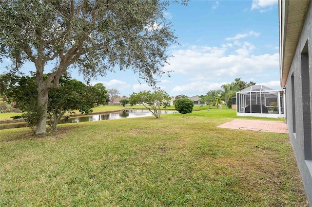 view of yard featuring a lanai, a patio area, and a water view