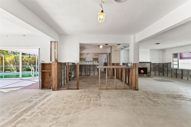 interior space with concrete flooring and a stone fireplace