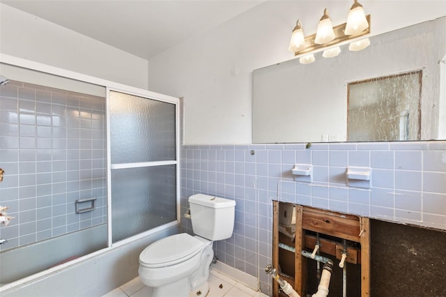 bathroom featuring combined bath / shower with glass door, tile patterned floors, tile walls, and toilet