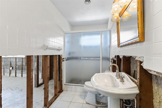 bathroom with tile patterned floors, sink, toilet, and tile walls