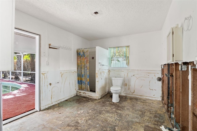 bathroom with a shower with shower curtain, a textured ceiling, and toilet